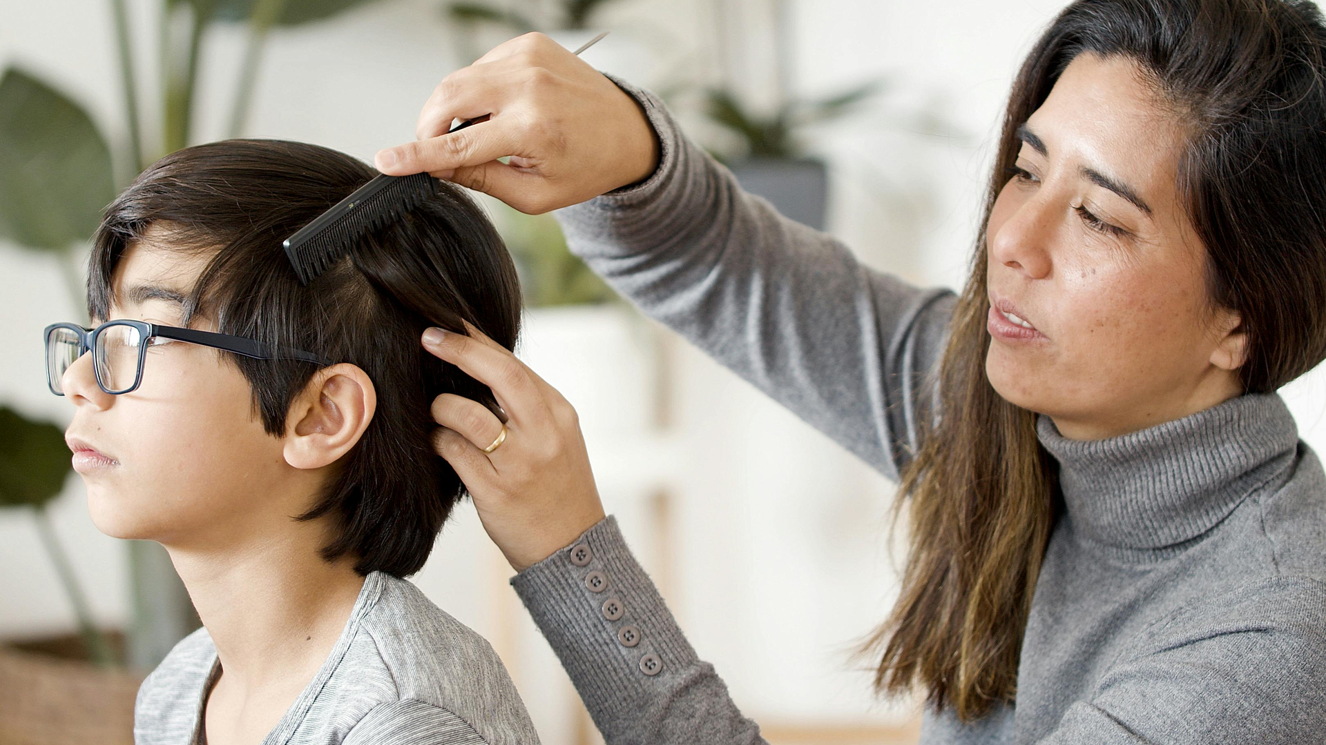 Mother combing through her child's hair with a fine-tooth comb during a lice head check